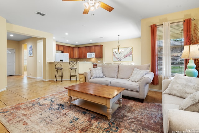 tiled living room featuring ceiling fan with notable chandelier