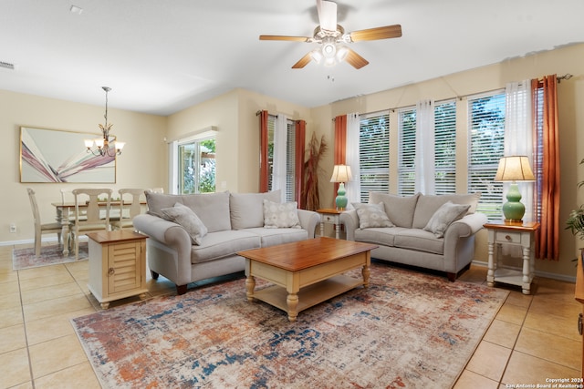 tiled living room featuring ceiling fan with notable chandelier