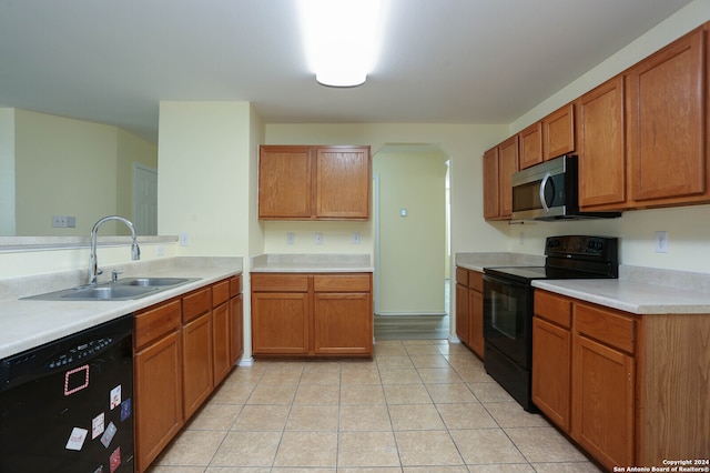 kitchen with light tile patterned flooring, sink, kitchen peninsula, and black appliances