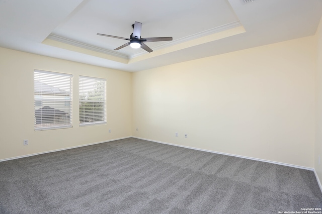 carpeted empty room featuring a raised ceiling, ornamental molding, and ceiling fan