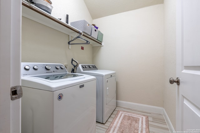 clothes washing area featuring light hardwood / wood-style flooring and washing machine and dryer