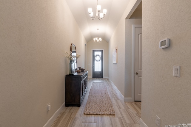 entrance foyer featuring light wood-type flooring, a chandelier, and vaulted ceiling