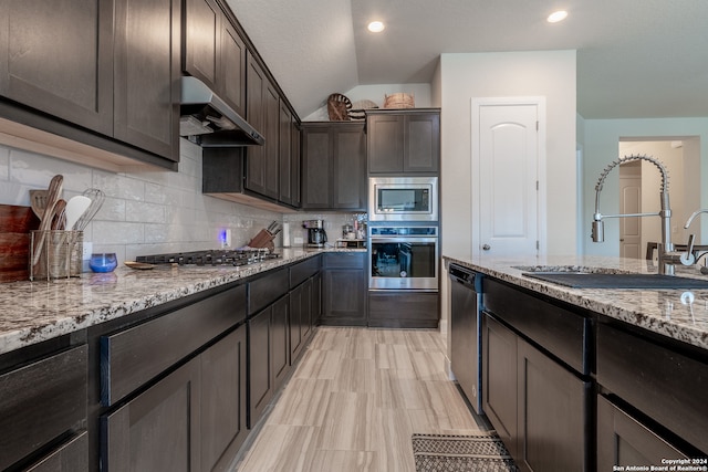 kitchen with lofted ceiling, sink, dark brown cabinets, exhaust hood, and appliances with stainless steel finishes