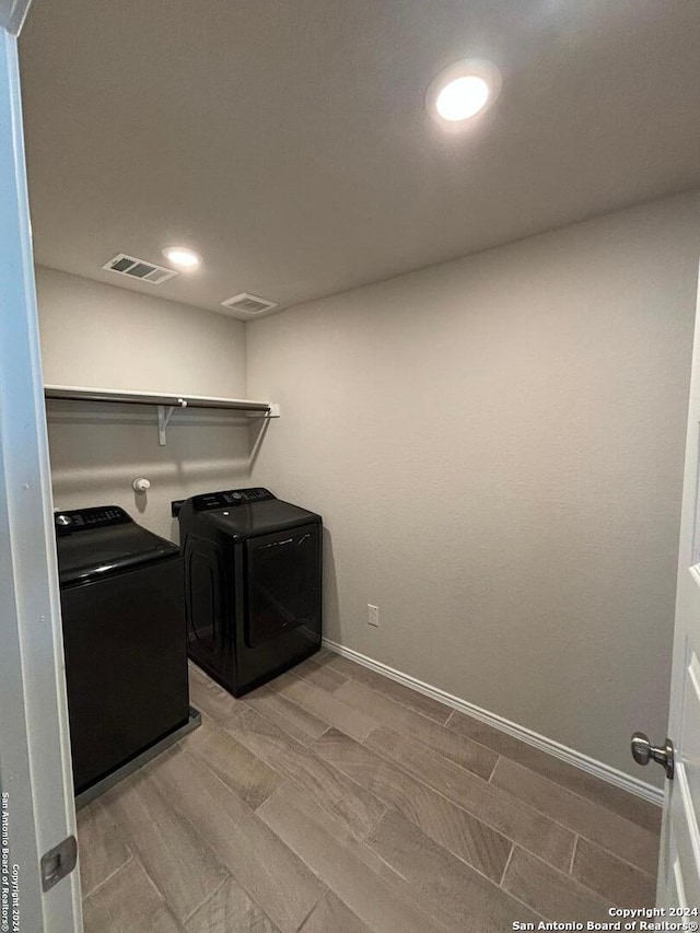 clothes washing area with light hardwood / wood-style floors and independent washer and dryer