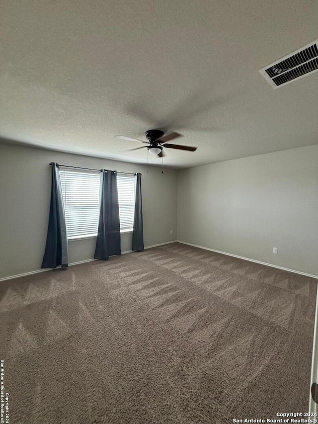 spare room featuring a textured ceiling, carpet, and ceiling fan