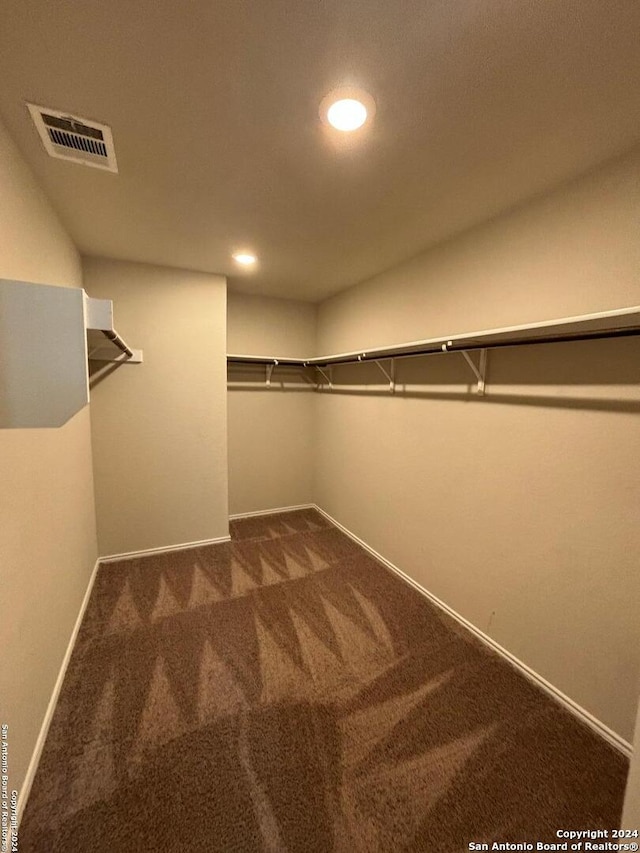 spacious closet with dark colored carpet