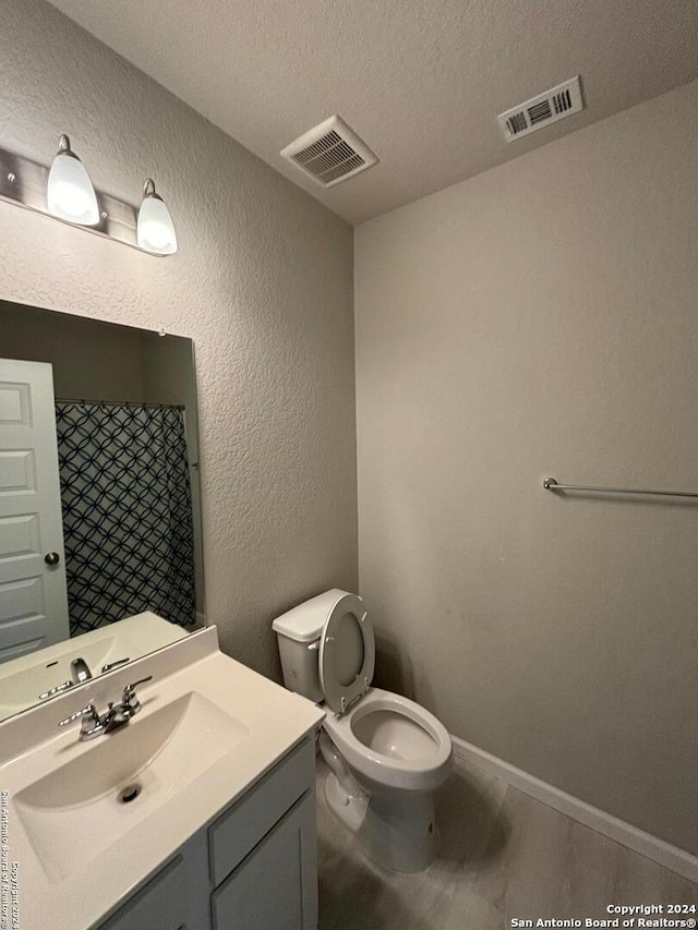 bathroom with a shower with shower curtain, a textured ceiling, vanity, and toilet