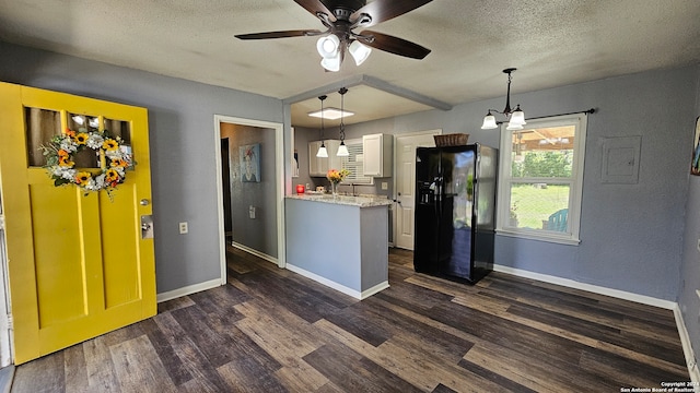 kitchen featuring hanging light fixtures, ceiling fan with notable chandelier, dark hardwood / wood-style floors, and black fridge