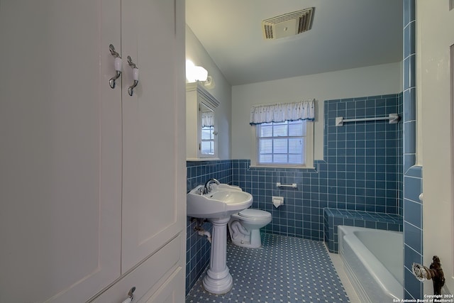 full bathroom featuring tile walls, tiled shower / bath, tile patterned floors, and toilet