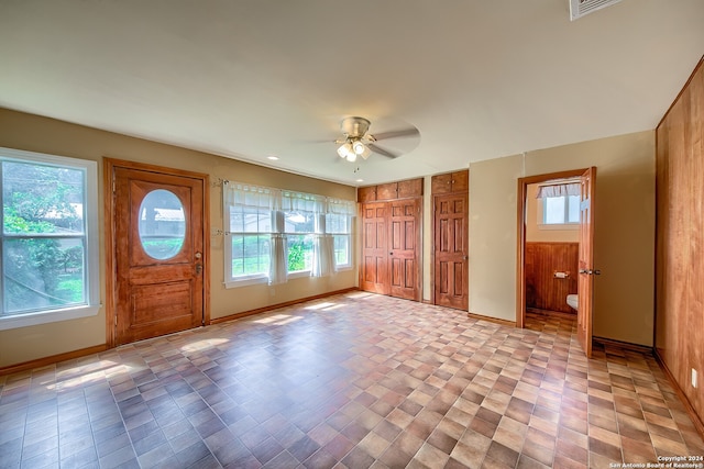 entryway with ceiling fan and wood walls