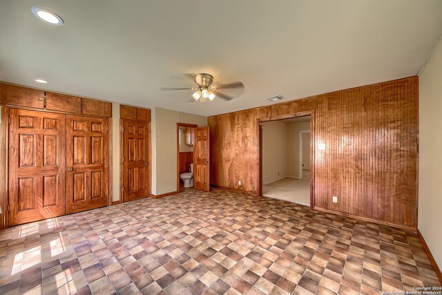 interior space featuring ceiling fan and wooden walls