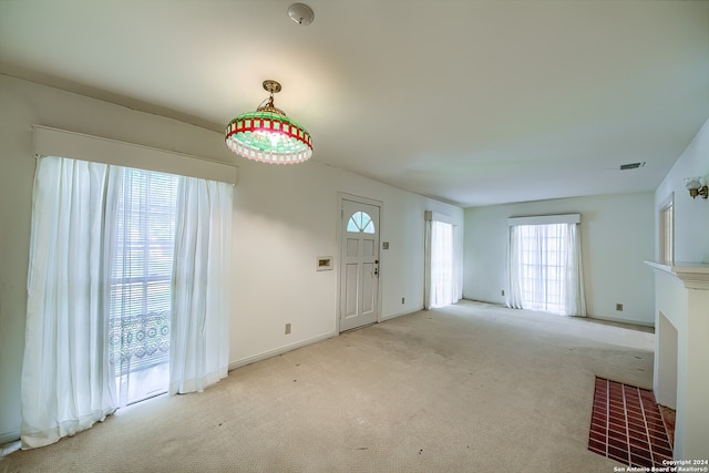 unfurnished living room featuring light colored carpet, a fireplace, and plenty of natural light