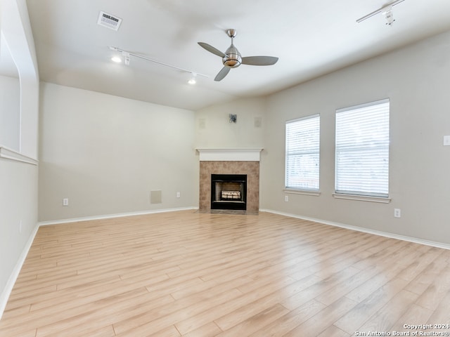 unfurnished living room featuring ceiling fan, light wood-type flooring, a fireplace, and rail lighting