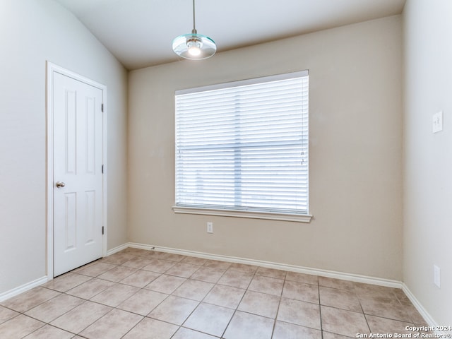 tiled spare room featuring lofted ceiling