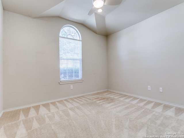 carpeted empty room featuring vaulted ceiling and ceiling fan