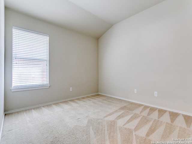 unfurnished room with vaulted ceiling and light carpet