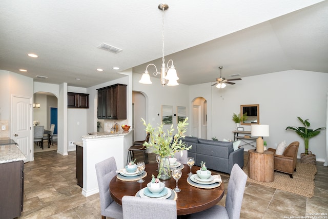 dining space with ceiling fan with notable chandelier and vaulted ceiling