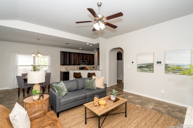 living room with ceiling fan with notable chandelier and vaulted ceiling