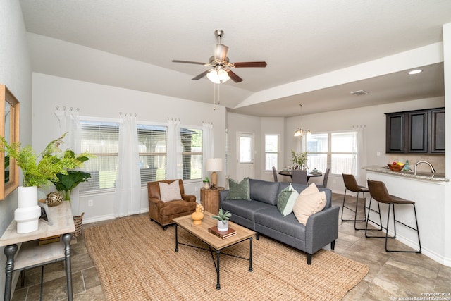 living room featuring ceiling fan with notable chandelier and sink