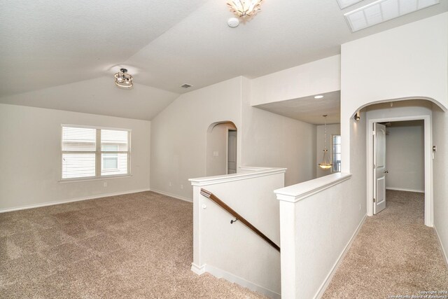 spare room with light colored carpet and lofted ceiling