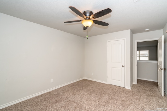 unfurnished bedroom with a textured ceiling, carpet flooring, and ceiling fan