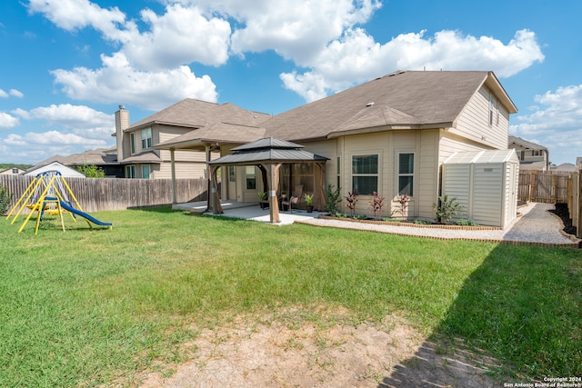 back of property with a playground, a gazebo, a storage shed, a lawn, and a patio area