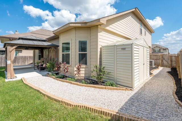 view of side of home with a storage shed, central AC unit, a patio area, and a gazebo