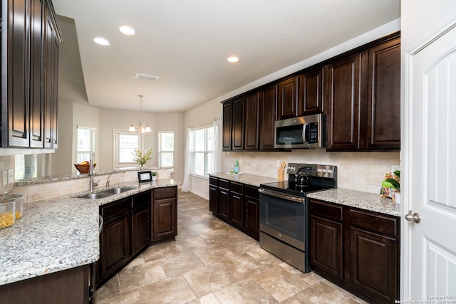 kitchen featuring appliances with stainless steel finishes, pendant lighting, dark brown cabinetry, sink, and a chandelier