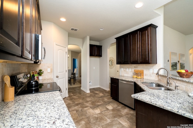 kitchen featuring light stone counters, stainless steel appliances, sink, and decorative backsplash