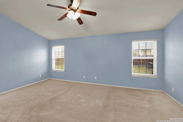 carpeted empty room with ceiling fan, vaulted ceiling, and a healthy amount of sunlight