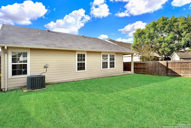 rear view of house with a lawn and central AC unit