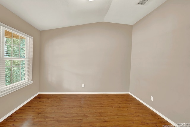 unfurnished room featuring lofted ceiling and hardwood / wood-style floors