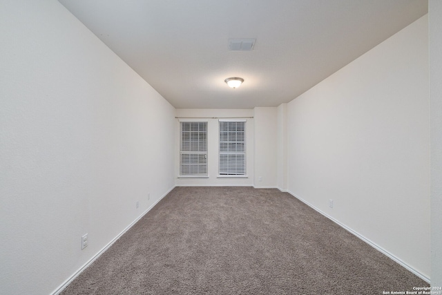 empty room featuring carpet flooring, visible vents, and baseboards