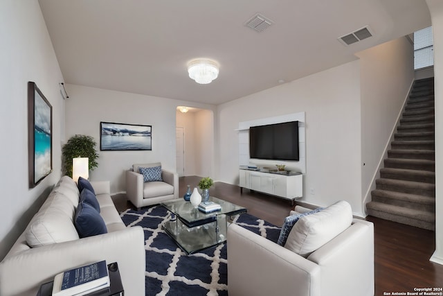 living area with dark wood-style flooring, visible vents, and stairs