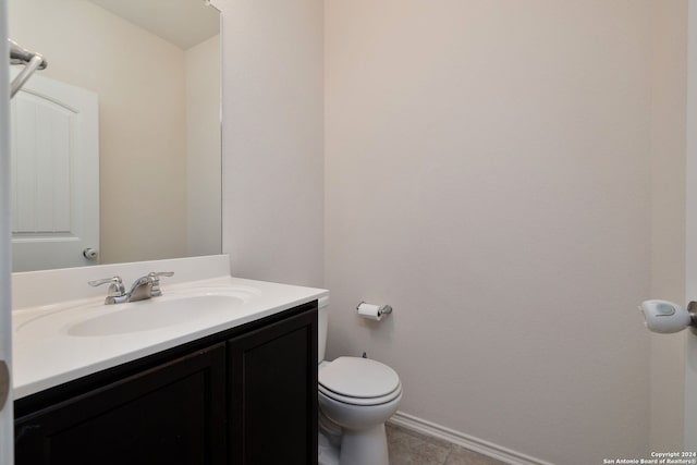 half bathroom featuring toilet, tile patterned flooring, vanity, and baseboards