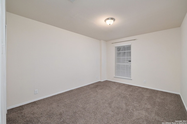 unfurnished room with dark carpet and baseboards