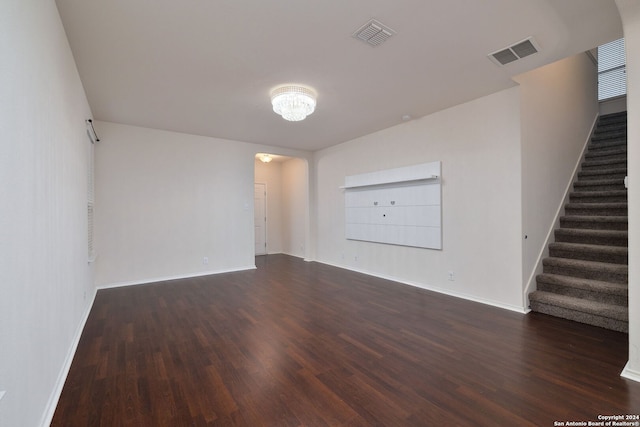 unfurnished room featuring dark wood-style flooring, stairway, visible vents, and baseboards