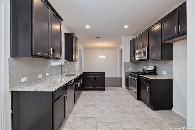 kitchen with dark brown cabinetry, a sink, appliances with stainless steel finishes, light stone countertops, and pendant lighting