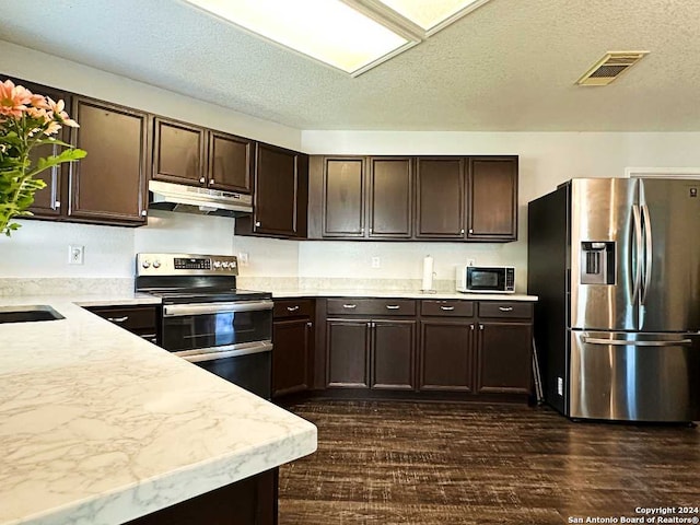 kitchen featuring dark brown cabinets, a textured ceiling, stainless steel appliances, and dark hardwood / wood-style flooring