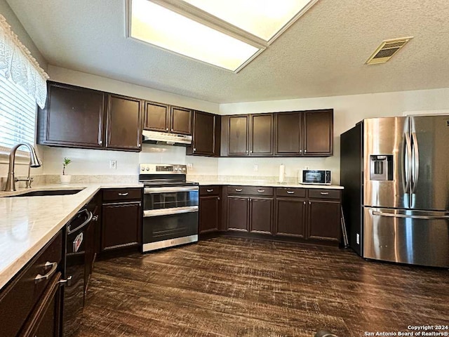 kitchen with sink, dark brown cabinets, a textured ceiling, stainless steel appliances, and dark hardwood / wood-style floors