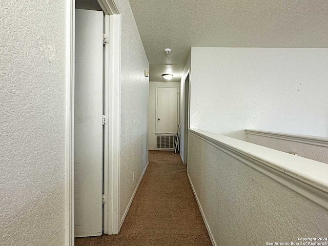 corridor with a textured ceiling and light colored carpet