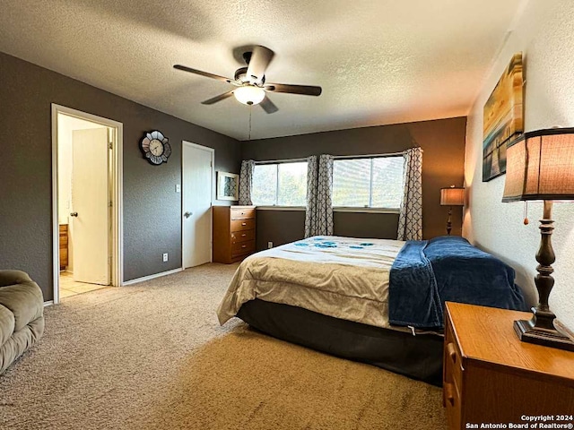 bedroom with ceiling fan, light colored carpet, a textured ceiling, and ensuite bathroom