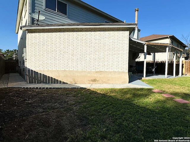 view of side of home featuring a lawn and a patio area