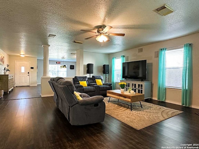 living room featuring ceiling fan, a textured ceiling, dark hardwood / wood-style floors, and ornate columns