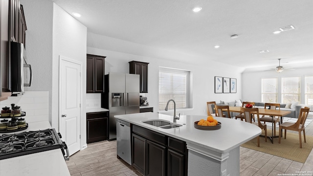 kitchen featuring a kitchen island with sink, sink, light hardwood / wood-style flooring, appliances with stainless steel finishes, and ceiling fan