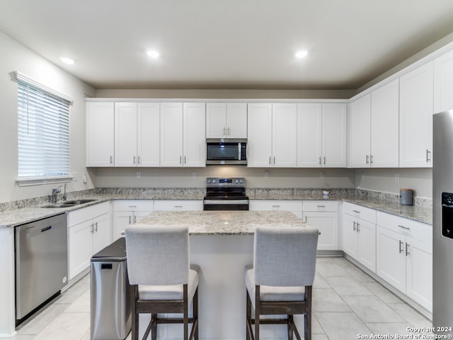 kitchen with white cabinets, appliances with stainless steel finishes, sink, and a center island