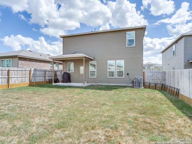 rear view of property featuring a lawn and central air condition unit