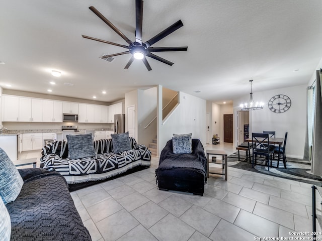 tiled living room with ceiling fan with notable chandelier