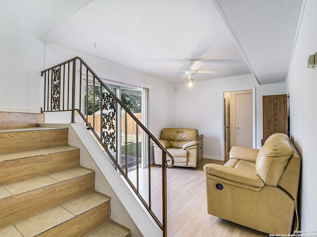 stairs with a textured ceiling, ceiling fan, and hardwood / wood-style flooring