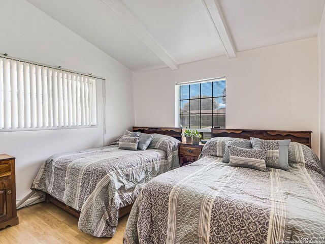 bedroom featuring light wood-type flooring and lofted ceiling with beams